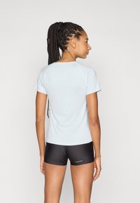 Ljusblå kortärmad träningsskjorta med rund halsringning, ihop med svarta shorts. Tyget verkar slätt med en figursydd design.