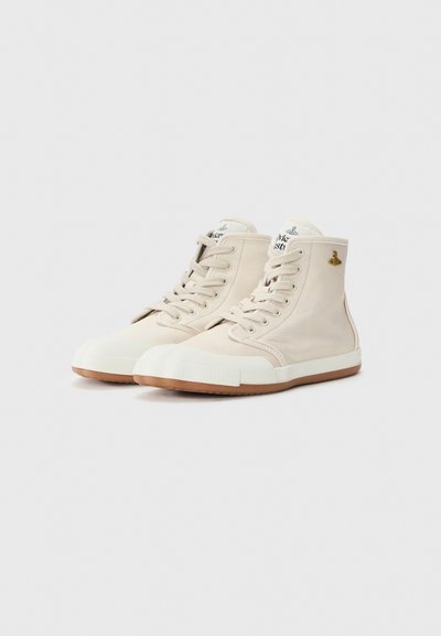 Beige hög topp sneakers med en slät canvasöverdel, vit gummikappan, och en ljusbrun gummisula. Har snörning och logodetalj.