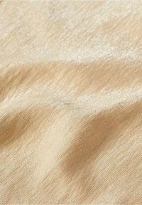 Tissu en satin de couleur beige clair, présentant une texture lisse avec un léger brillant et de fines rayures horizontales.