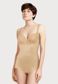 Nu nude formuojantis bodysuit'as su nėriniuotu liemenėliu, reguliuojamomis petnešomis ir glotnia danga. Yra iškirpimo detalė krūtinėje ir sagties uždarymas.