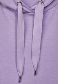 Lila hoodie med mjuk tygstruktur, försedd med dragsnören och metallagg, som visar en avslappnad design.