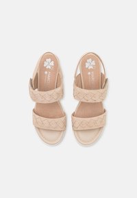 Beige sandals with two wide braided straps, open toe, and a low heel. The insole features a floral logo on a light tan background.
