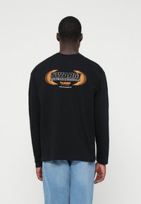Tricou negru cu mânecă lungă, având grafică "SWARM INTERNATIONALS" în portocaliu și alb. Material din bumbac, croială lejeră, design cu gât rotund.