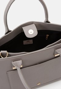 Szara syntetyczna torba z teksturowaną powierzchnią, złotymi elementami metalowymi i kieszenią na zamek wewnątrz. Posiada dwa mocne uchwyty i metkę.