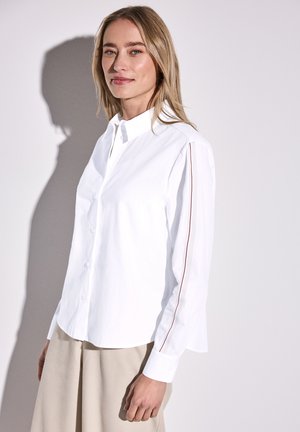 White button-up shirt with a collar, featuring red accent stripes on sleeves and a curved hem; made from smooth cotton fabric.