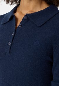 Granatowa koszulka polo wykonana z miękkiej dzianiny, z trzema guzikami i dyskretnym haftowanym logo na piersi.