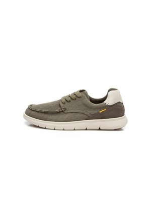 Zapatilla de tela gris con una suela de goma blanca lisa, punta redondeada y cordones planos a juego, con un acento en el tacón de color marrón contrastante.