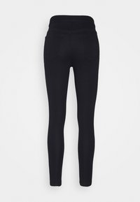 Leggings negros con una textura suave, cintura alta y dos bolsillos traseros, ajustados desde la cintura hasta el tobillo.