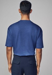 Marineblå kortærmet t-shirt med rund hals, lavet af glat stof. Ser let figursyet ud ved skuldrene med et rent, enkelt design.
