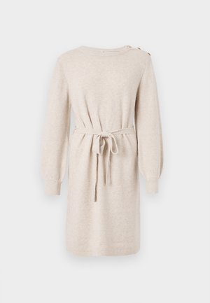 Beige stickad klänning med långa ärmar, åtsittande midjeband, rund halsringning och knappdetaljer på axeln. Mjuk textur, knä längd.