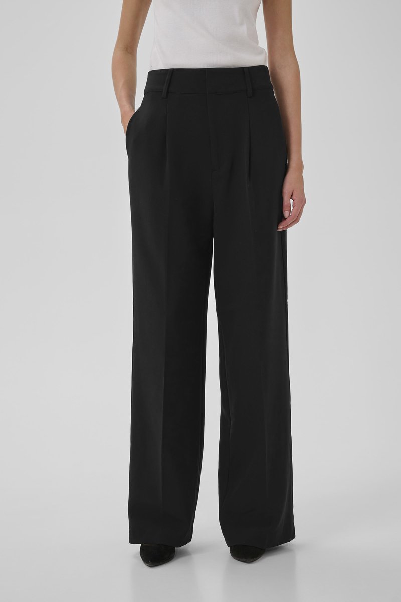 Svarta vida byxor i slät tyg, med hög midja och sidofickor. De når ankeln med en ren, skräddarsydd finish.