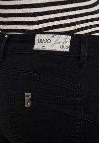 Svarta denim jeans med en Liu Jo-lapp på midjebandet. Har subtila sömmar, en liten metallaccent på bakficka och en slim fit.