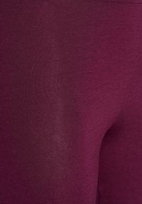 Bordeauxfarbene Leggings aus glattem, dehnbarem Material, in einfarbigem Design und schlanker, taillierter Passform.