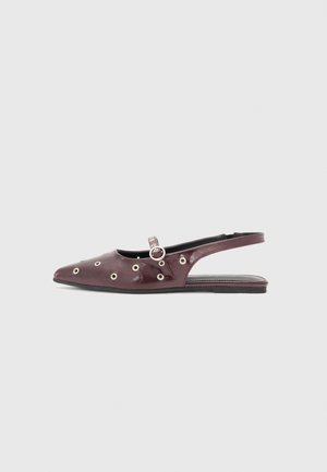 Mocassin slingback pointu bordeaux avec détails en œillets argentés et une petite lanière à boucle sur le dessus, vu de profil sur fond gris.