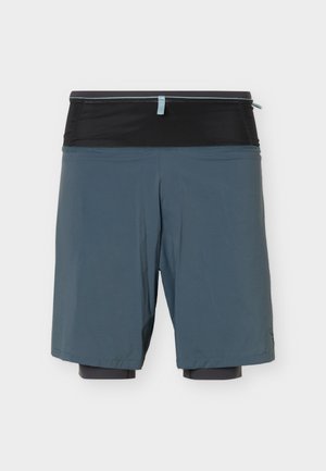 Ανδρικό αθλητικό σορτς δύο στρωμάτων με μαύρο εσωτερικό συμπιεστικό στρώμα και χαλαρό μπλε εξωτερικό στρώμα, εμφανιζόμενο σε λευκό φόντο.