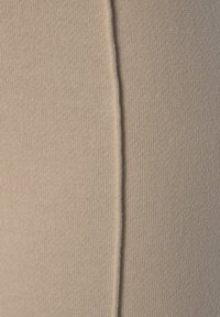 Beiger Strickstoff mit glatter Textur. Vertikale Nahtdetails verleihen subtilen visuellen Reiz. Weiches und flexibles Material.