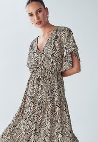 Dzīvnieku apdruka maxi kleita ar dziļu V-veida izgriezumu, īsām piedurknēm un elastīgu vidukli. Dizains ar plūstošu formu, bēšā un melnās svītras.