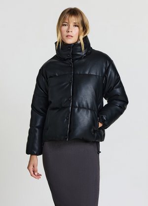 Black faux leather puffer jacket with a high collar, snap-button closure, and quilted design. Model is wearing a dark skirt.