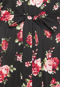 Czarna tkanina z czerwonymi i różowymi różami, zielonymi liśćmi oraz przewiązanym w kokardę paskiem materiałowym w talii.
