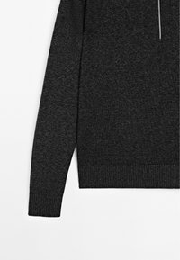 Pull en tricot gris foncé avec un col rond, des manches longues et des poignets et ourlet côtelés. Le matériau a une texture douce et un motif subtil.