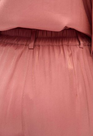 Miękka różowa tkanina o gładkiej fakturze, z elastycznym pasem i subtelnymi fałdami. Projekt zapewnia komfort i swobodę ruchów.