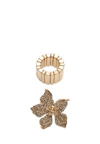 Set di gioielli in tono oro composto da un anello scanalato e da una spilla a forma di fiore adornata con piccoli strass, evidenziando dettagli e textures intricati.