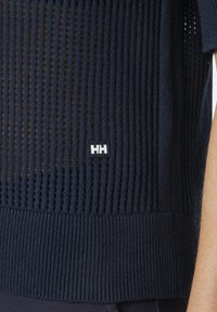 Námořnický pletený top s texturovaným vzorem včelího plástu, s jednobarevným ribovaným výstřihem a lemem. Malá značka na spodním pravém okraji.