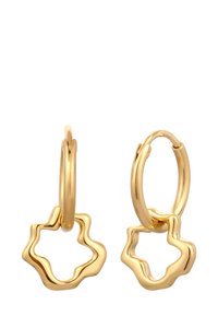 Goldene Creolen mit wellenförmigen, vierblättrigen Blumenanhängern, die von jeder Creole hängen, auf einem weißen Hintergrund.