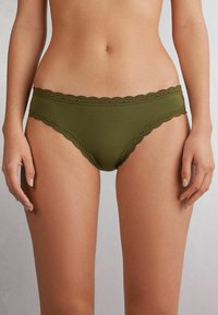 Olijfgroene katoenen bokser met kantafwerking en golvende randen, met een gladde textuur en een middenhoogte ontwerp.
