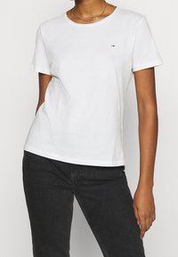 White cotton T-shirt with a classic crew neckline and short sleeves. Features a small logo on the chest and a relaxed fit.