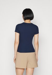 Marinblå, figursydd T-shirt med korta ärmar, tillverkad av ett mjukt, strukturerat tyg. Rundad halsringning och ribbade detaljer vid fåll.