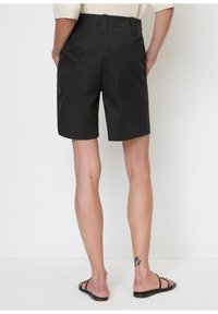 Sorte shorts lavet af et letvægtsstof, med en lige pasform, bæltestropper og en baglomme. Glat overflade med minimalistisk detaljer.