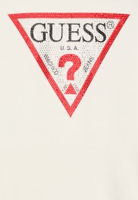 Baltas audinys su dideliu raudonu trikampiu logotipu, puoštu studijomis, juodu tekstu ir raudonu centriniu klaustuku.