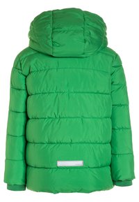 Veste d'hiver verte rembourrée avec une capuche, matelassage horizontal, poignets côtelés et une petite étiquette réfléchissante rectangulaire en bas du dos.