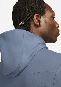 Hooded pullover in soft, textured blue fabric. Features a fitted hood and subtle seam detailing on the back.