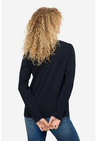 Navyblaues Langarmoberteil aus weichem Stoff, mit einem schlichten Design und geradem Schnitt, kombiniert mit blauen Jeans.