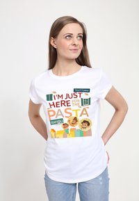 Bílá bavlněná tričko s barevným potiskem, na kterém je text "Jsem tu jen kvůli těstovinám" a kreslené obličeje na přední straně.