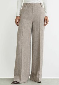 Laiade püksid tekstuurse beežikangaga, millel on peened mustrid, kõrge vöökoht ja küljetaskud. Kaunistatud viimistletud viimistlusega.