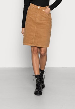 Brown corduroy knee-length skirt with a front seam, two side pockets, and button closure, paired with black lace-up combat boots.