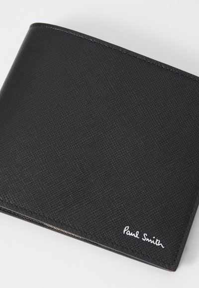 Svart lommebok laget av teksturert lær, med et minimalistisk design som har hvit "Paul Smith" branding og subtile søm detaljer.
