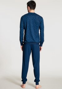 Pyjamas marine avec un haut à manches longues orné de petits points bleu clair et un pantalon assorti avec des poignets élastiques. Tissu doux et respirant.