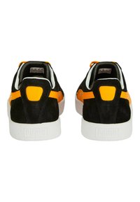 Mustat ja oranssit mokkasandaalit valkoisilla kumipohjilla, joissa on kontrastivärinen kantapää ja sivuaitteet. Yksinkertainen, matala profiili.