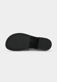 Semelle de chaussure noire vue du dessous, surface lisse avec une légère texture au talon, taille 37 marquée près de la voûte plantaire.