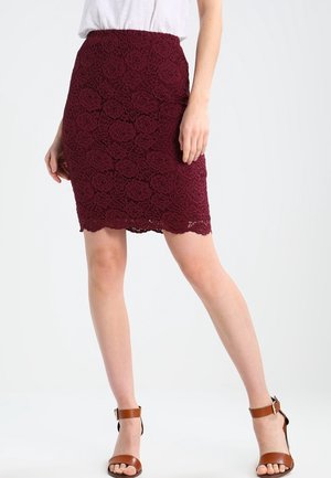 Bordeauxrode kanten potloodrok met bloemenpatroon, golvende zoom, midilengte, gecombineerd met bruine sandalen met hak en bandjes.