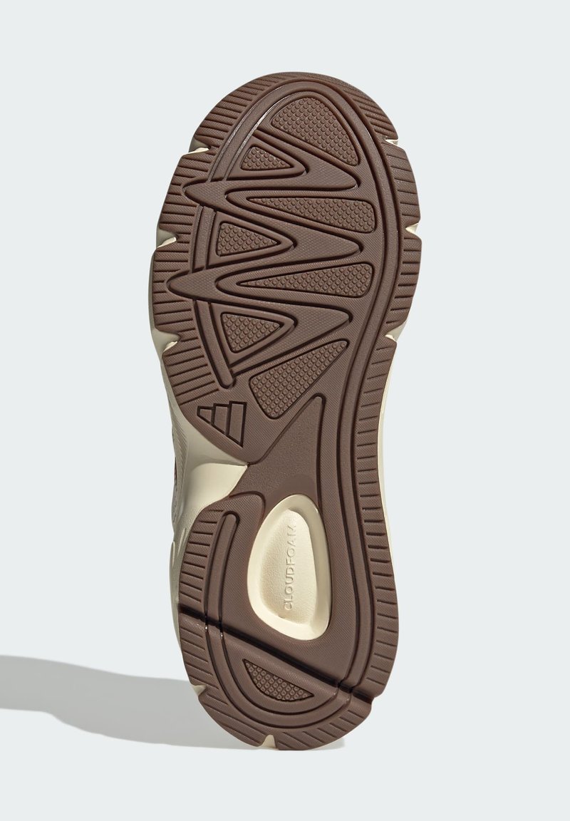 Suola di scarpa in gomma marrone con una superficie testurizzata, caratterizzata da motivi a zigzag e accenti curvi. Il design include dettagli di colore chiaro.