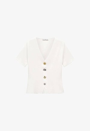 White short-sleeve top with a V-neck, featuring five decorative buttons in gold, silver, grey, and patterned designs down the center.