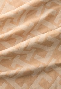 Woven fabric in light peach with a textured zigzag pattern in a slightly darker shade, creating a subtle contrast across the surface.