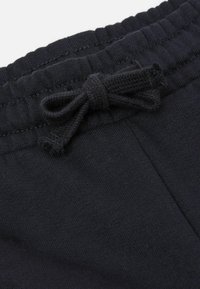 Schwarze Baumwoll-Sweatpants mit einem elastischen Bund, der vorne mit einer dekorativen Schleife verziert ist, aus einem weichen, strukturierten Stoff.