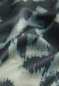 Textured fabric featuring a dark blue-black base with a soft pastel pattern in shades of green and beige, creating a fluid, flowing appearance.