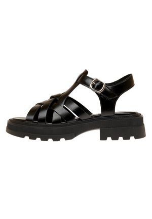 Schwarze Ledersandale mit grob profillierter Sohle, gekreuzten Riemen, T-Riemen-Design und verstellbarer silberner Schnalle am Knöchelriemen.